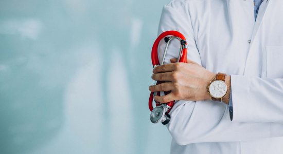 Young handsome physician in a medical robe with stethoscope